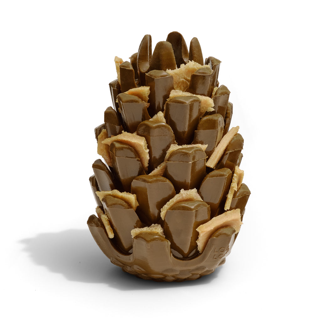 The Loblolly Pinecone Puzzle Dog Toy by Loblola. There are turkey jerky treats tucked behind each scale of the pinecone.